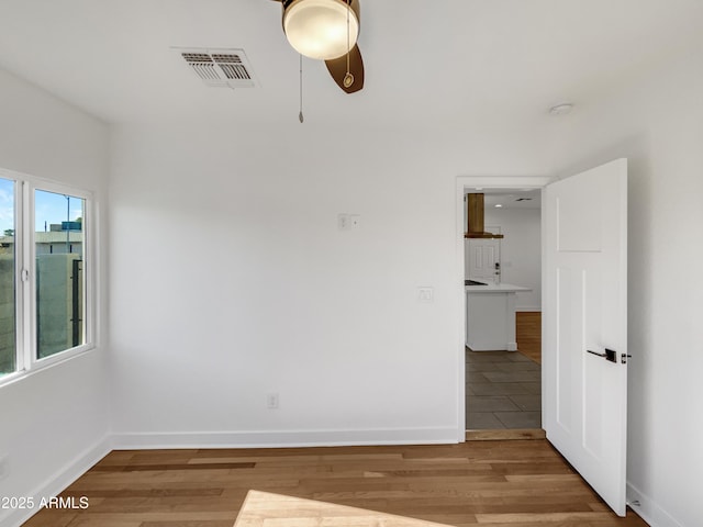 empty room with ceiling fan, light hardwood / wood-style flooring, and a healthy amount of sunlight