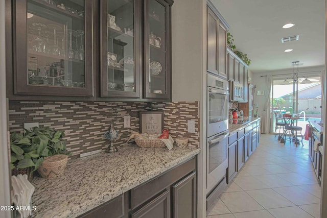 kitchen with glass insert cabinets, visible vents, decorative backsplash, and light tile patterned flooring