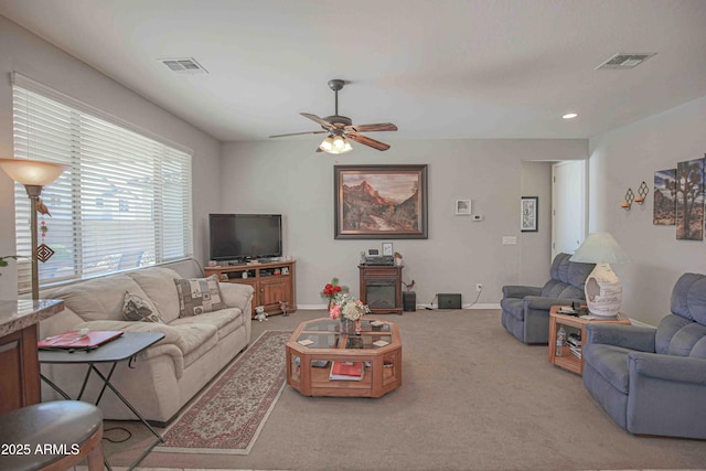 carpeted living room featuring baseboards, visible vents, and a ceiling fan