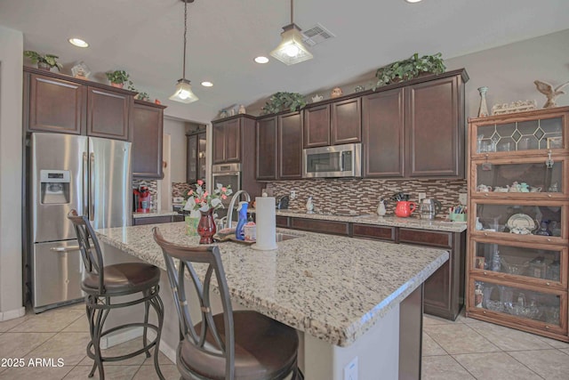 kitchen featuring appliances with stainless steel finishes, light tile patterned flooring, a sink, and visible vents