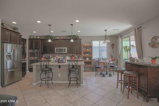 kitchen with a breakfast bar area, light tile patterned floors, visible vents, appliances with stainless steel finishes, and dark brown cabinetry