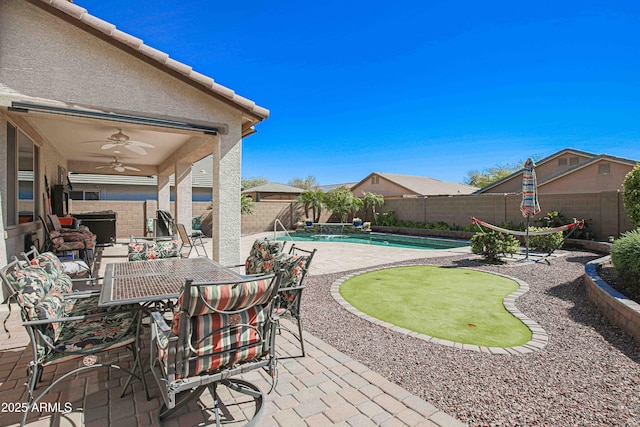 view of patio / terrace with a fenced backyard, a ceiling fan, a fenced in pool, and outdoor dining space