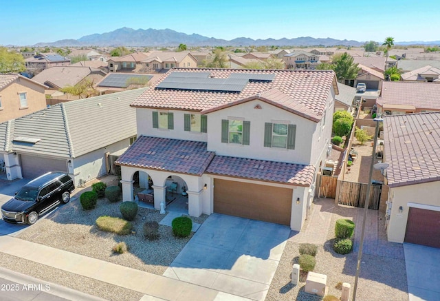 mediterranean / spanish-style home with a mountain view, driveway, a tile roof, and a residential view