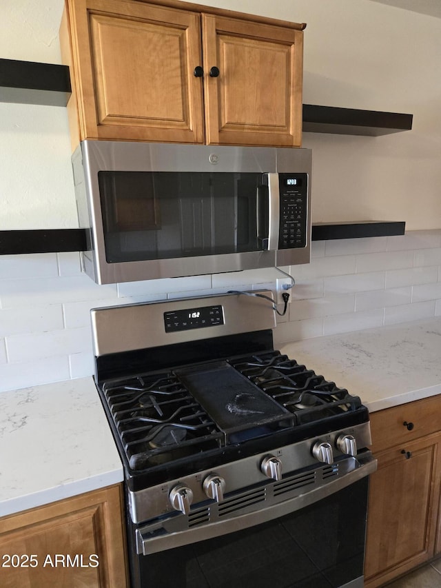 kitchen with backsplash, light stone countertops, and stainless steel appliances