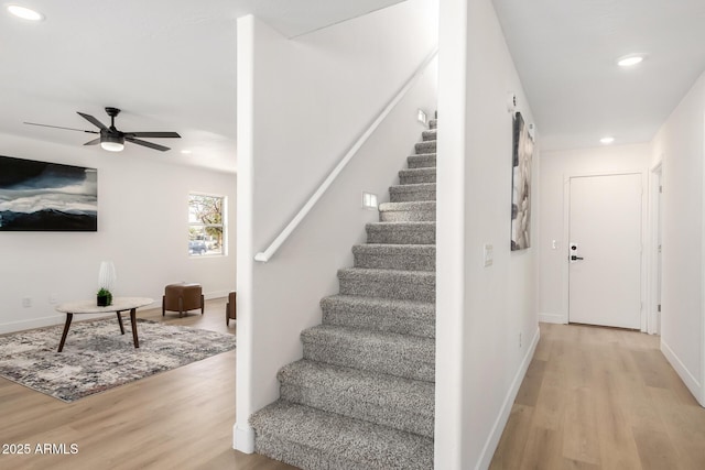 stairs with baseboards, a ceiling fan, wood finished floors, and recessed lighting