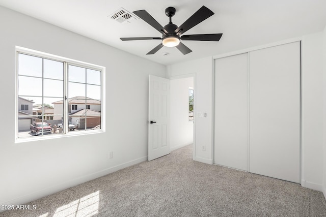 unfurnished bedroom featuring carpet, visible vents, a ceiling fan, a closet, and baseboards