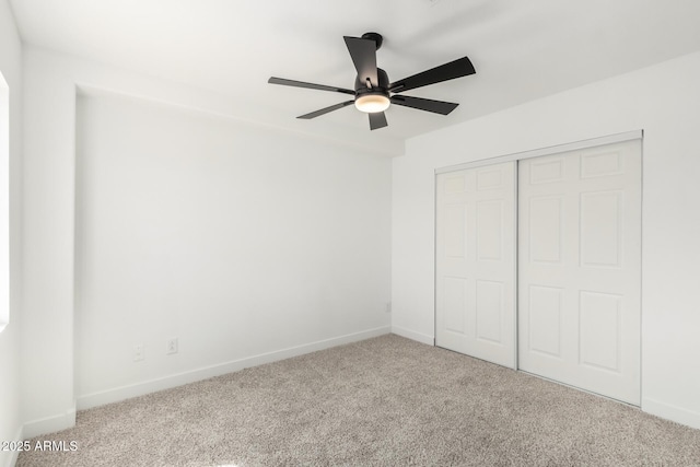 unfurnished bedroom featuring baseboards, carpet floors, a closet, and ceiling fan