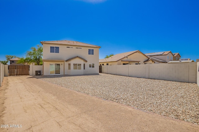 back of property with a tile roof, a fenced backyard, a gate, and stucco siding
