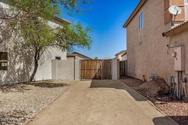 view of side of property featuring a gate, fence, and stucco siding