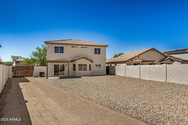 back of house with a gate, a fenced backyard, a tiled roof, and stucco siding