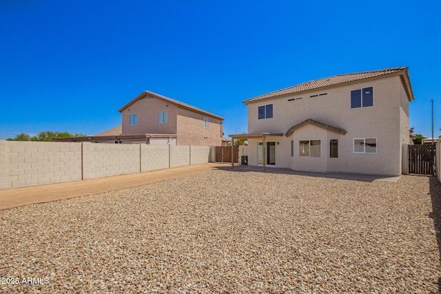 rear view of house with a patio, a fenced backyard, a tiled roof, and stucco siding