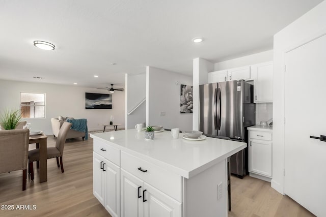 kitchen featuring white cabinets, a center island, freestanding refrigerator, light wood-style floors, and ceiling fan
