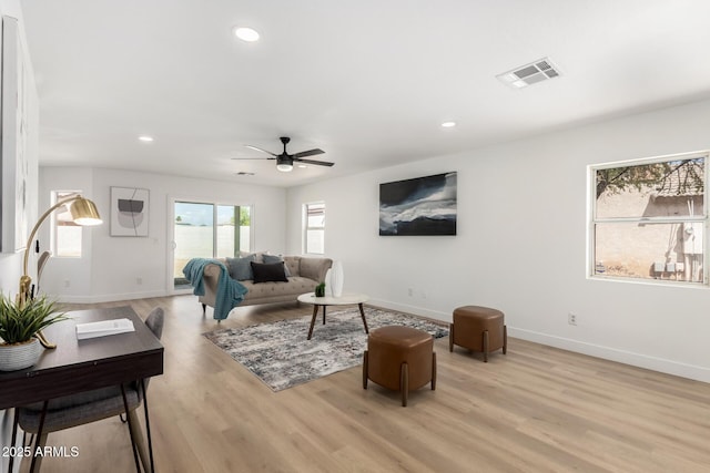 living room featuring ceiling fan, baseboards, light wood-style floors, and visible vents