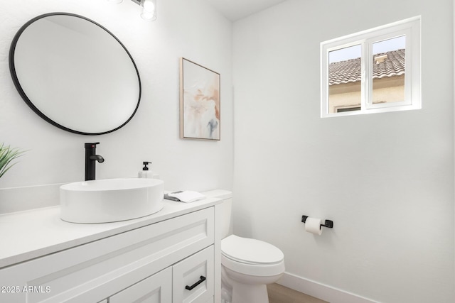 bathroom with toilet, vanity, and baseboards