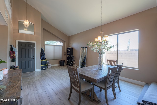 dining area with light hardwood / wood-style floors, high vaulted ceiling, and a notable chandelier