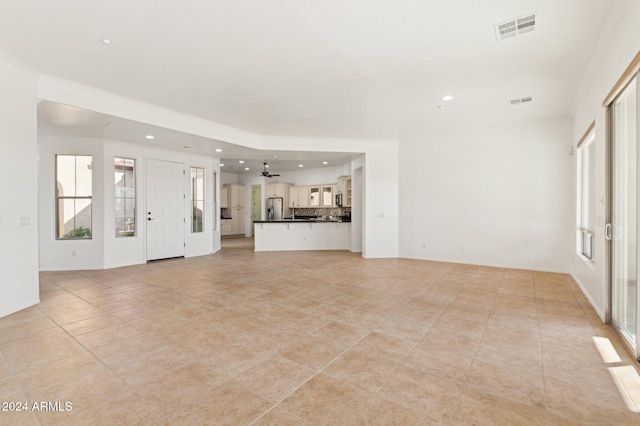 unfurnished living room with ceiling fan, ornamental molding, and light tile patterned floors