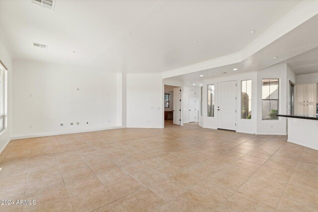 unfurnished living room with light tile patterned floors and ornamental molding