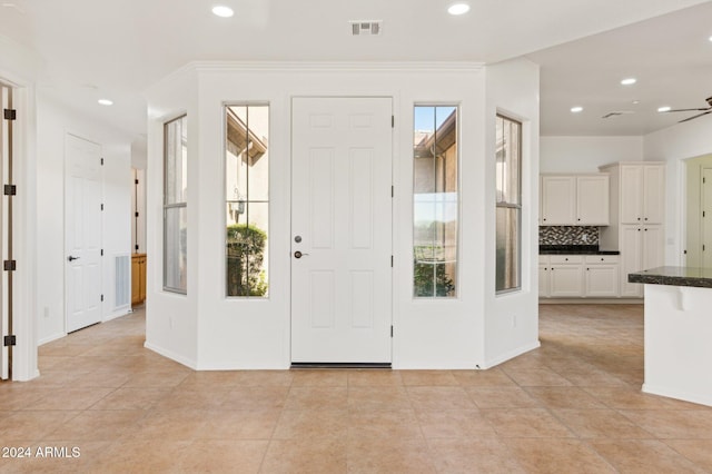 tiled foyer entrance featuring ornamental molding, ceiling fan, and a healthy amount of sunlight