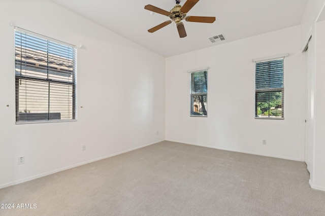 unfurnished room with ceiling fan, light colored carpet, and a healthy amount of sunlight