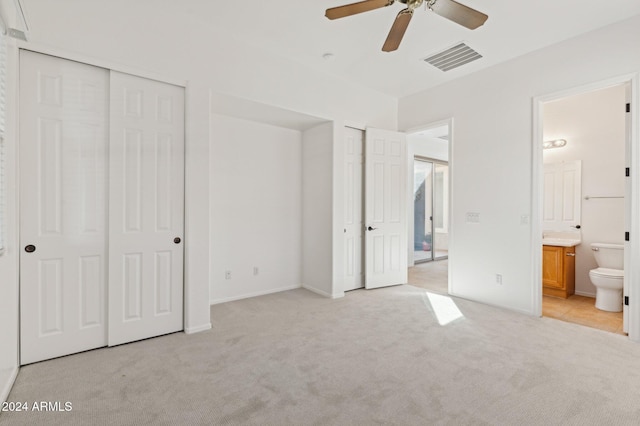 unfurnished bedroom with ensuite bath, ceiling fan, light carpet, and multiple closets