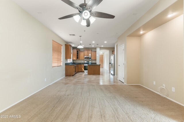 unfurnished living room featuring visible vents, light carpet, baseboards, and a ceiling fan