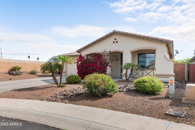 mediterranean / spanish-style house with stucco siding, a tile roof, fence, concrete driveway, and an attached garage