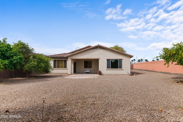 rear view of property with a patio, a tiled roof, a fenced backyard, and stucco siding