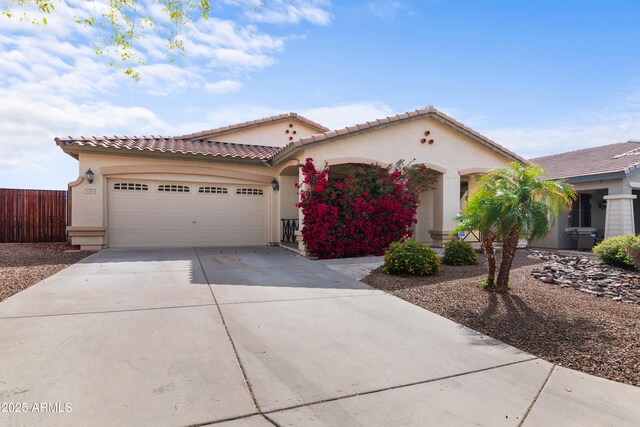 mediterranean / spanish-style house featuring concrete driveway, a tiled roof, an attached garage, and stucco siding