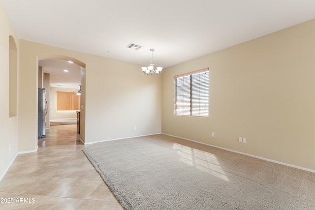 spare room featuring visible vents, arched walkways, an inviting chandelier, light tile patterned flooring, and baseboards