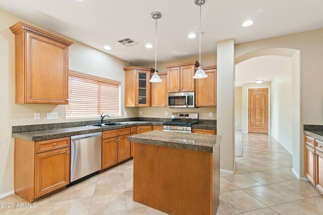 kitchen featuring visible vents, a sink, a center island, stainless steel appliances, and arched walkways