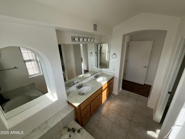 bathroom with a bathtub, tile patterned flooring, vanity, and vaulted ceiling