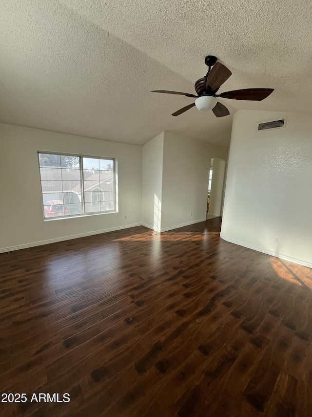 empty room with a textured ceiling, ceiling fan, dark hardwood / wood-style floors, and lofted ceiling