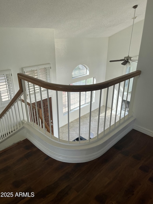 stairs with a textured ceiling, hardwood / wood-style flooring, and ceiling fan