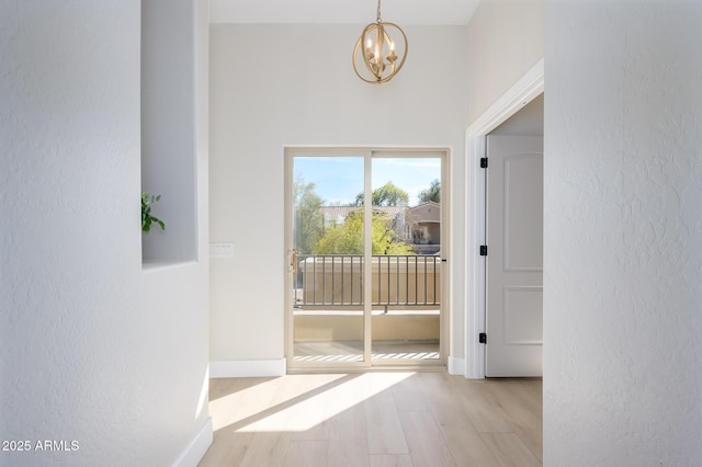 doorway to outside featuring a notable chandelier and light wood-type flooring