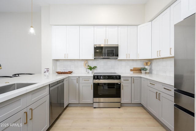 kitchen with tasteful backsplash, gray cabinets, stainless steel appliances, and light hardwood / wood-style floors