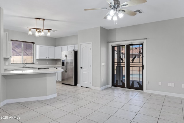 kitchen featuring sink, stainless steel fridge, white cabinetry, decorative light fixtures, and kitchen peninsula