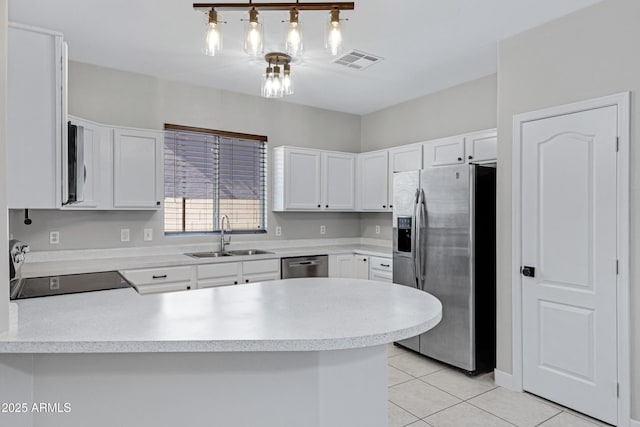 kitchen featuring sink, light tile patterned floors, appliances with stainless steel finishes, white cabinetry, and kitchen peninsula