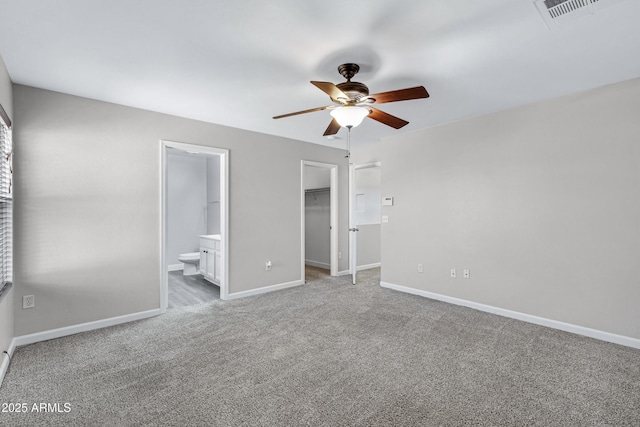 unfurnished bedroom featuring connected bathroom, a spacious closet, ceiling fan, light carpet, and a closet