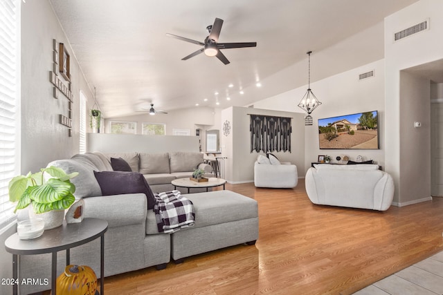 living room with lofted ceiling, light hardwood / wood-style flooring, and ceiling fan with notable chandelier