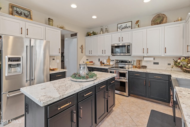 kitchen featuring tasteful backsplash, white cabinets, appliances with stainless steel finishes, and light tile patterned floors