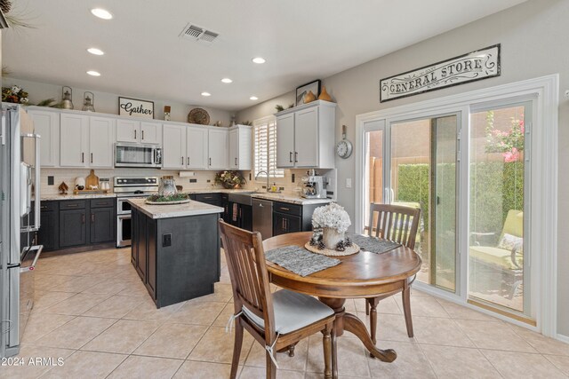 kitchen featuring tasteful backsplash, a kitchen island, white cabinets, appliances with stainless steel finishes, and light tile patterned floors