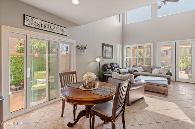 dining area with light tile patterned flooring, a towering ceiling, and a healthy amount of sunlight