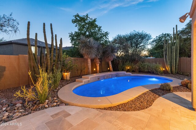 pool at dusk featuring a patio area