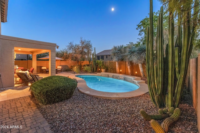 pool at dusk featuring a hot tub and a patio area