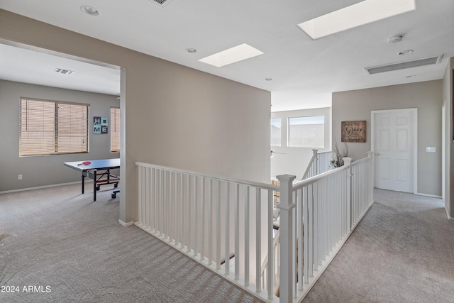 corridor with a skylight and light carpet