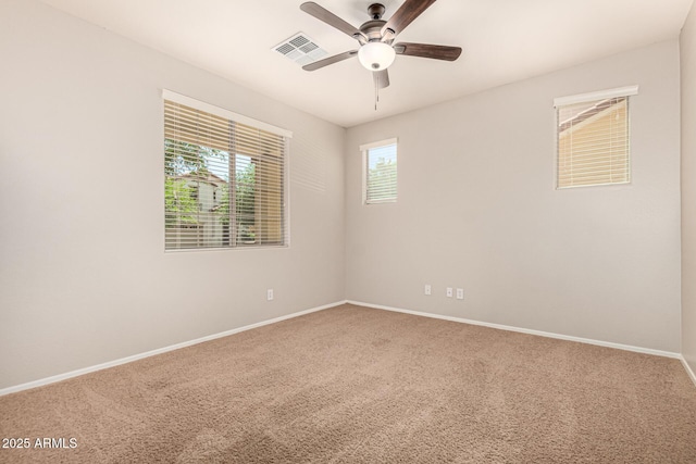carpeted spare room with visible vents, baseboards, and a ceiling fan