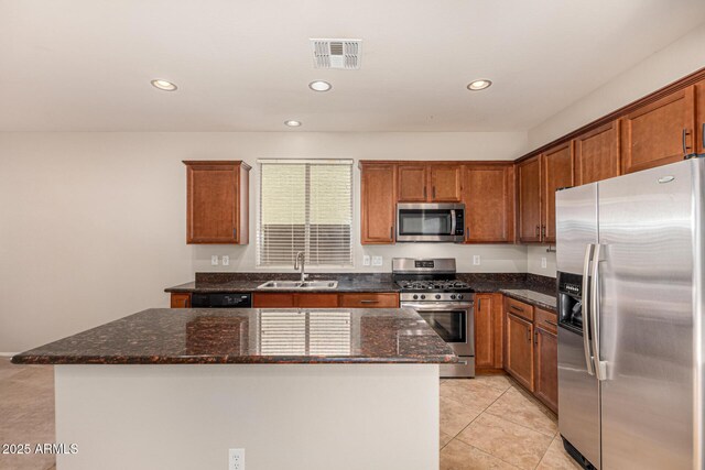 kitchen with visible vents, a center island, appliances with stainless steel finishes, dark stone countertops, and a sink