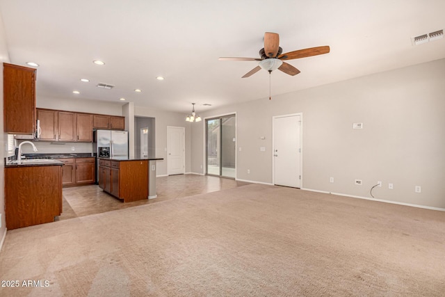 kitchen featuring visible vents, a center island, a sink, dark countertops, and light colored carpet
