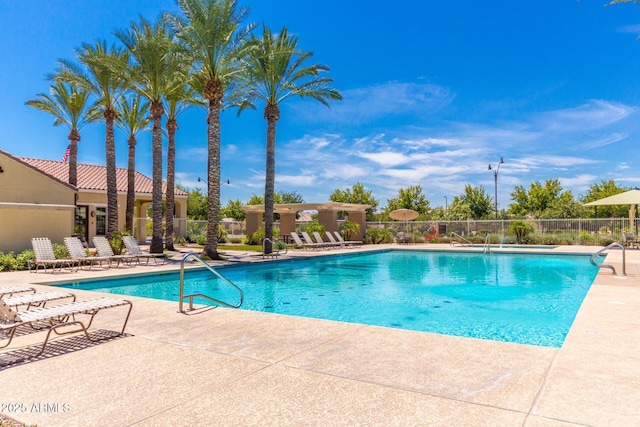 community pool with a patio area and fence