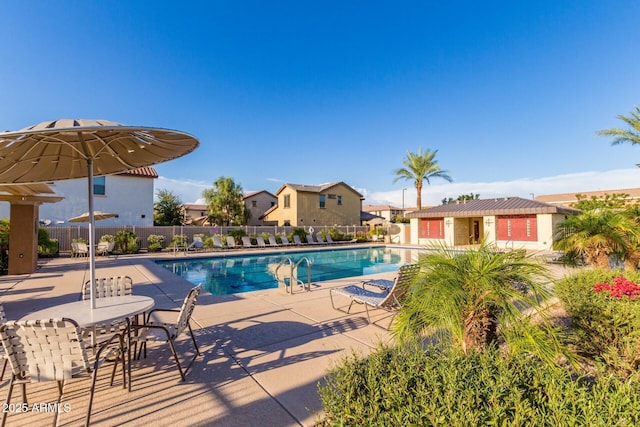 pool with a patio, an outbuilding, and fence